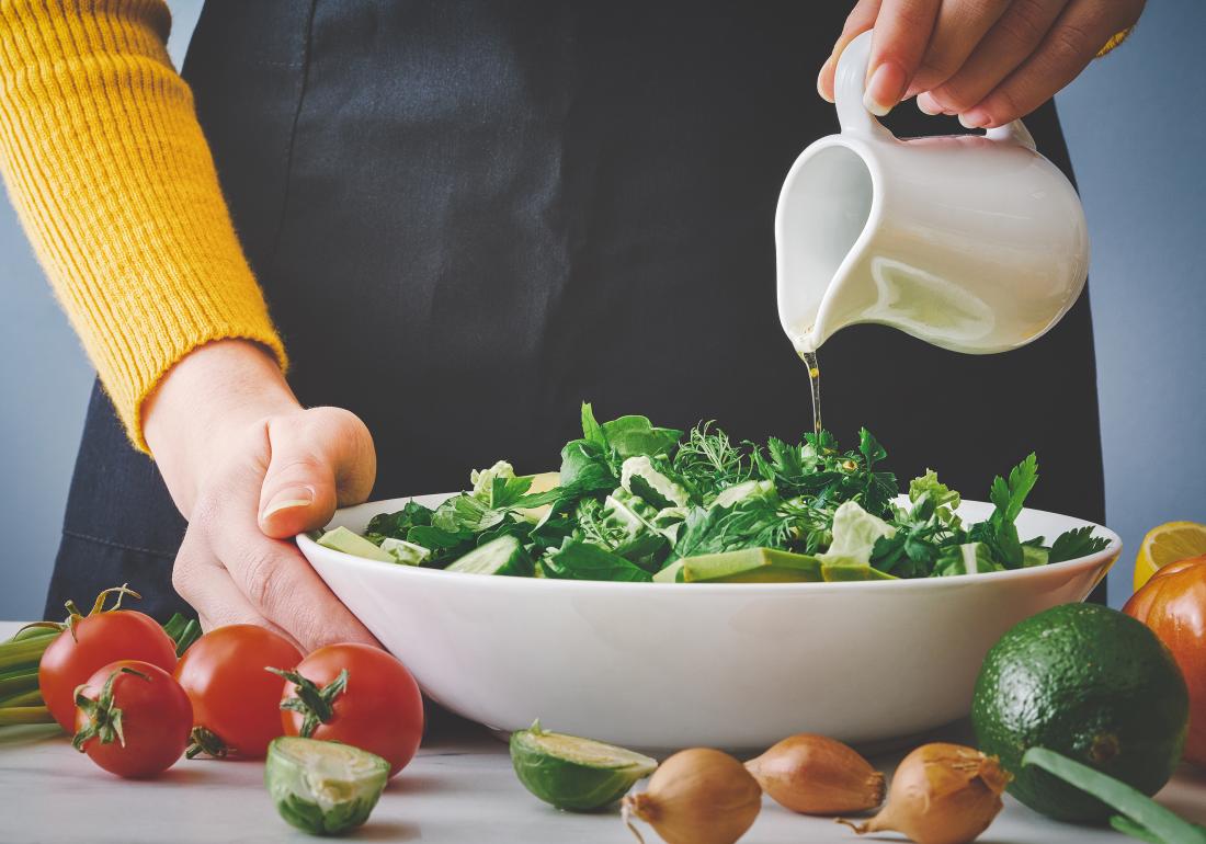 Pouring olive oil on salad