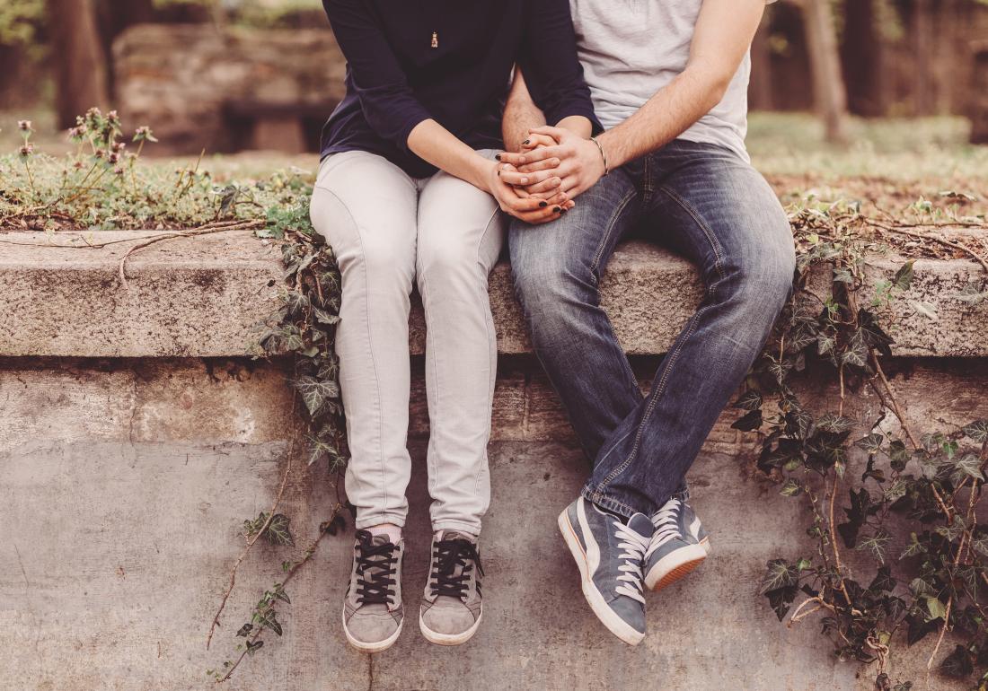 Couple sitting on wall holding hands