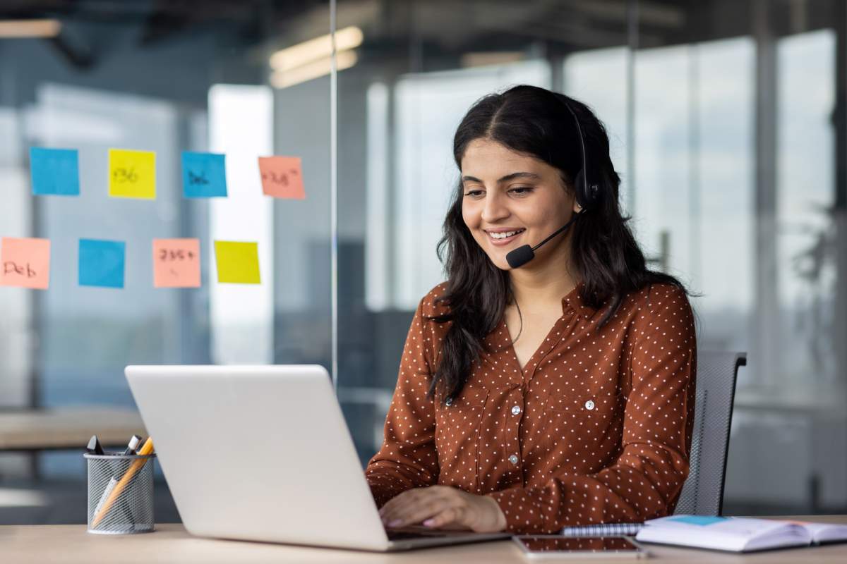 Woman speaking into headset working on laptop