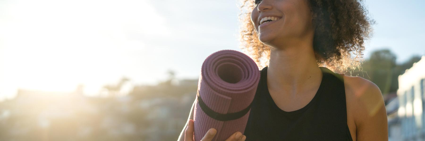 Woman holding yoga mat in exercise gear