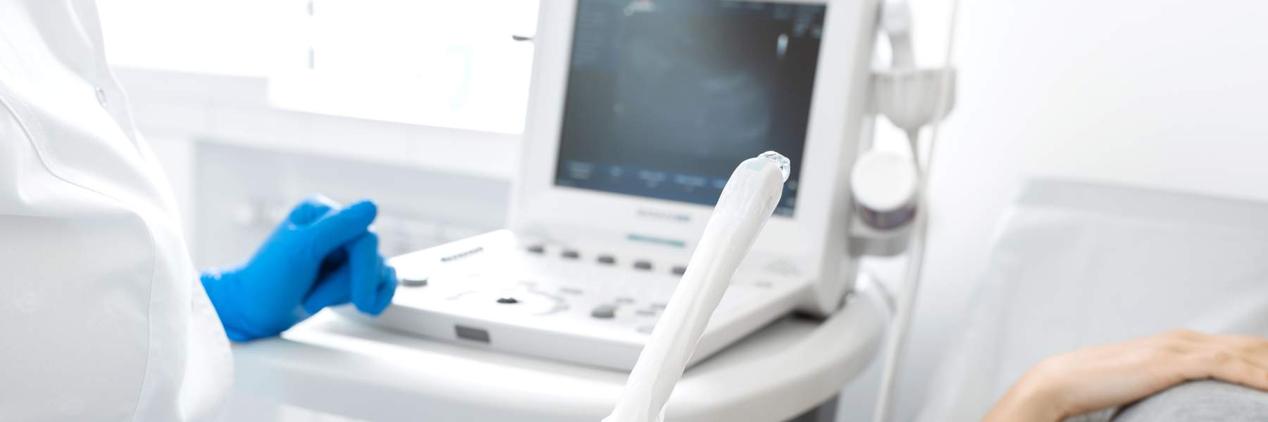 Gloved sonographer hand holding an ultrasound transducer