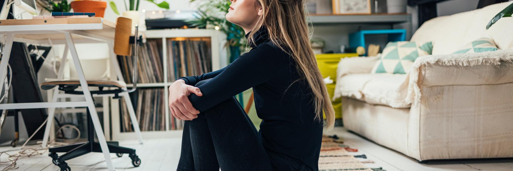 Woman sitting alone on the floor hugging her knees
