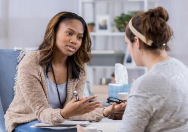 Two women speaking in an doctors office, one a doctor the other a patient