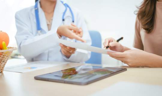 Female doctor helping patient fill out a form