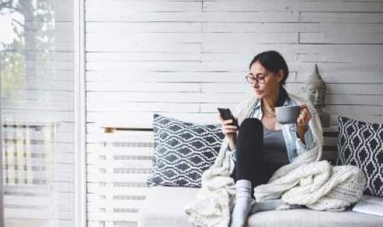 woman sitting down with phone and coffee